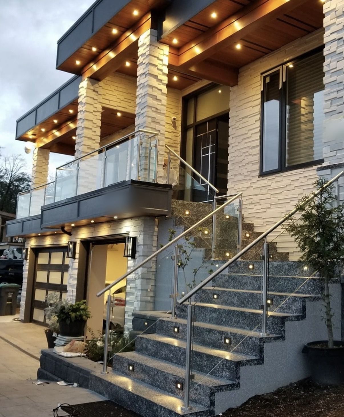 Exterior glass railings and cedar soffit lighting on a Metro Vancouver home at dusk