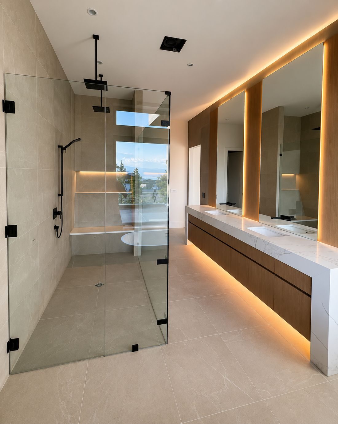 Frameless glass shower enclosure with matte black hardware beside an oak vanity
