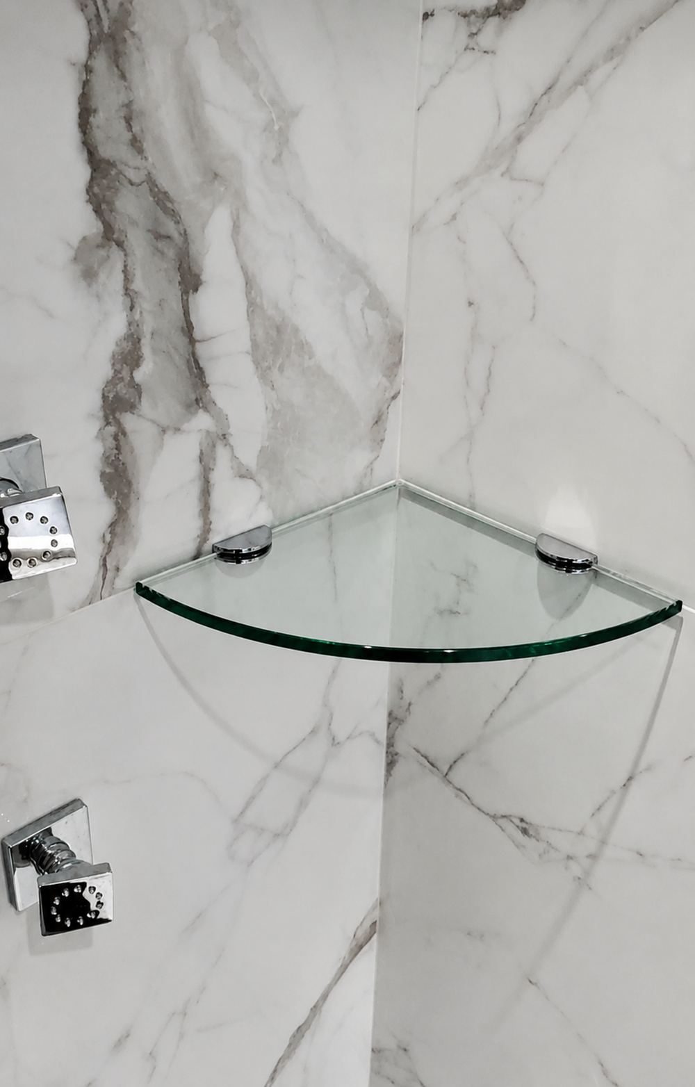 Custom glass corner shelf in a marble tiled shower