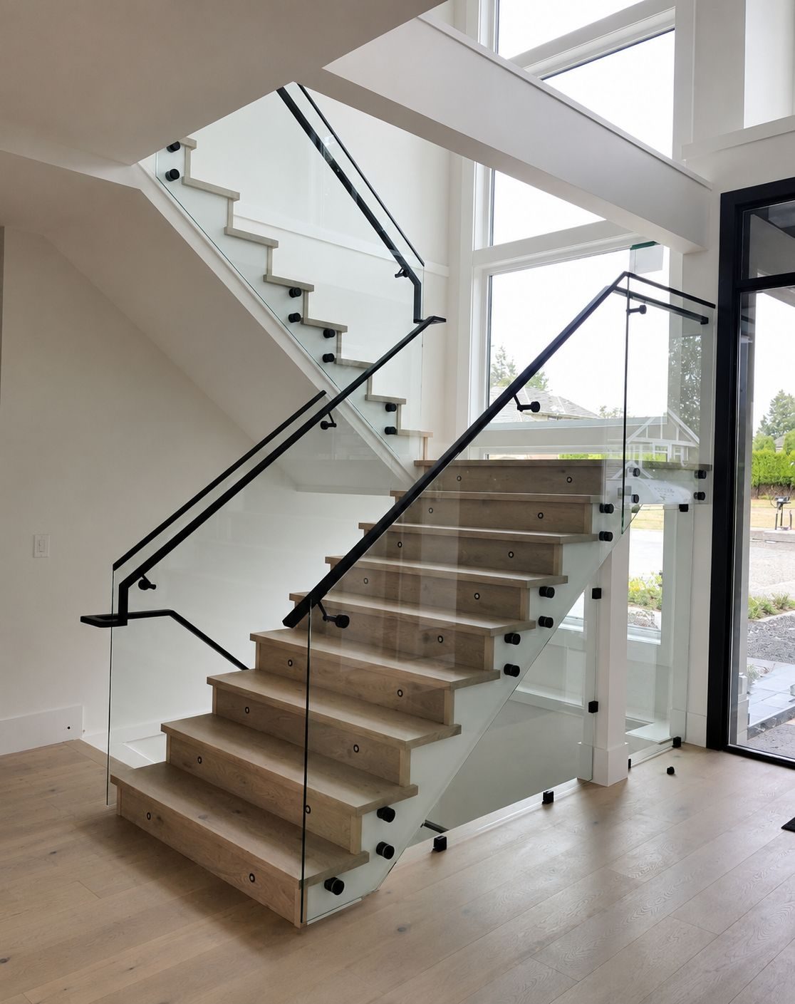White oak switchback staircase with frameless glass railing and matte black handrail