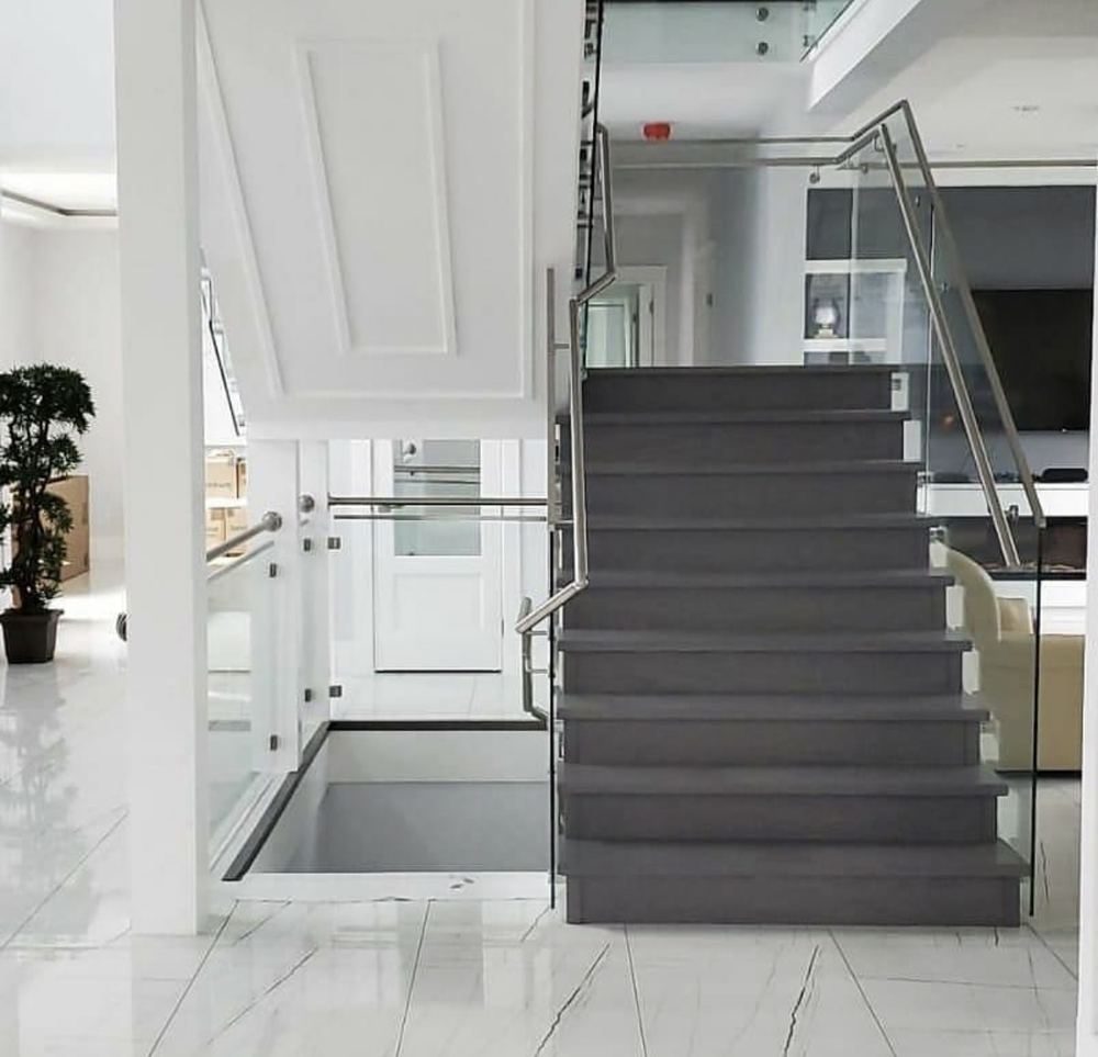 Stainless steel and glass staircase railing on marble flooring